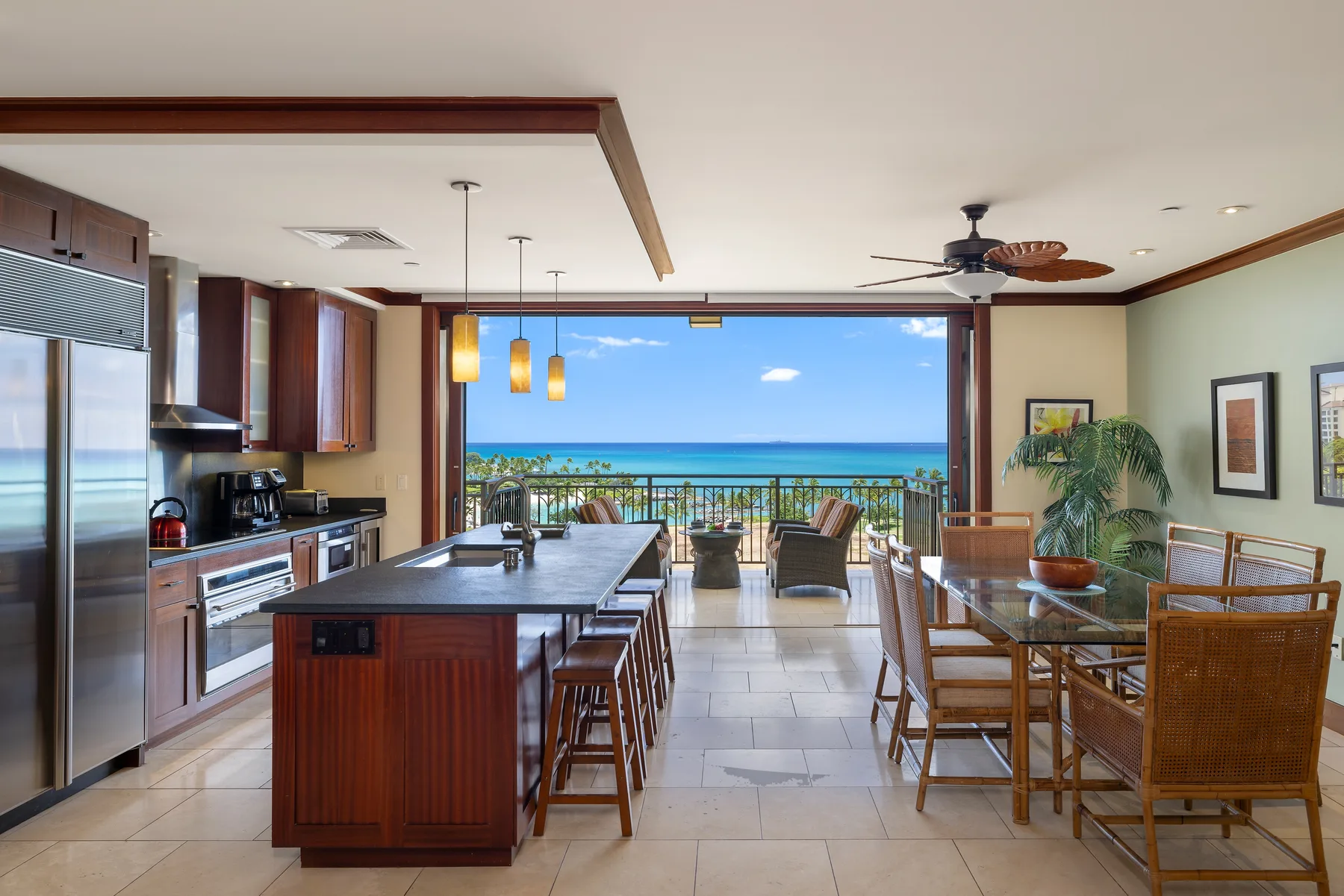 An open kitchen and dining area faces a balcony with an ocean view.