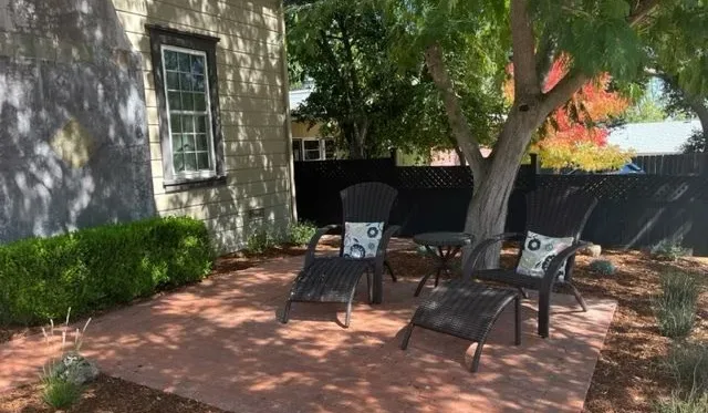 Un patio sombreado con asientos al aire libre bajo árboles frondosos.