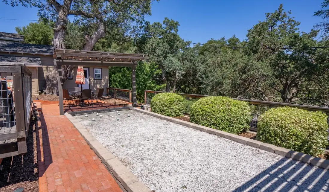 Un patio al aire libre con una zona de grava, un sendero de ladrillo y árboles alrededor.