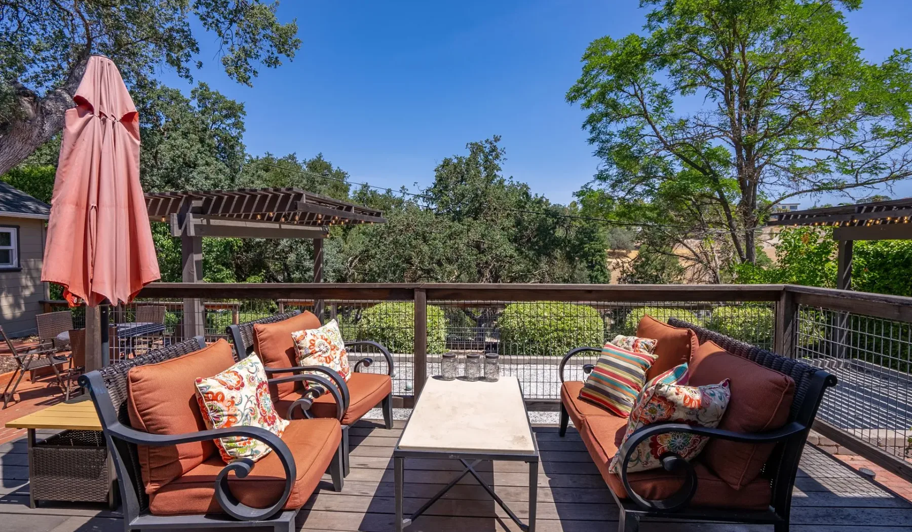 Una terraza exterior tiene asientos acolchados alrededor de una mesa baja.