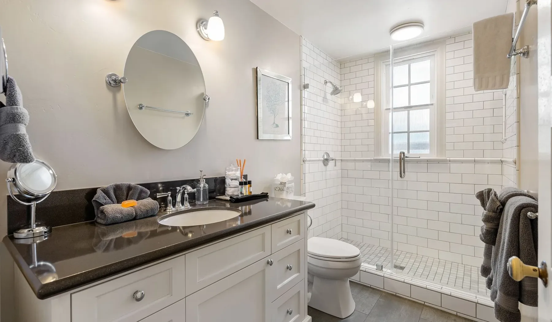 Un baño luminoso con tocador, inodoro y zona de ducha con azulejos.