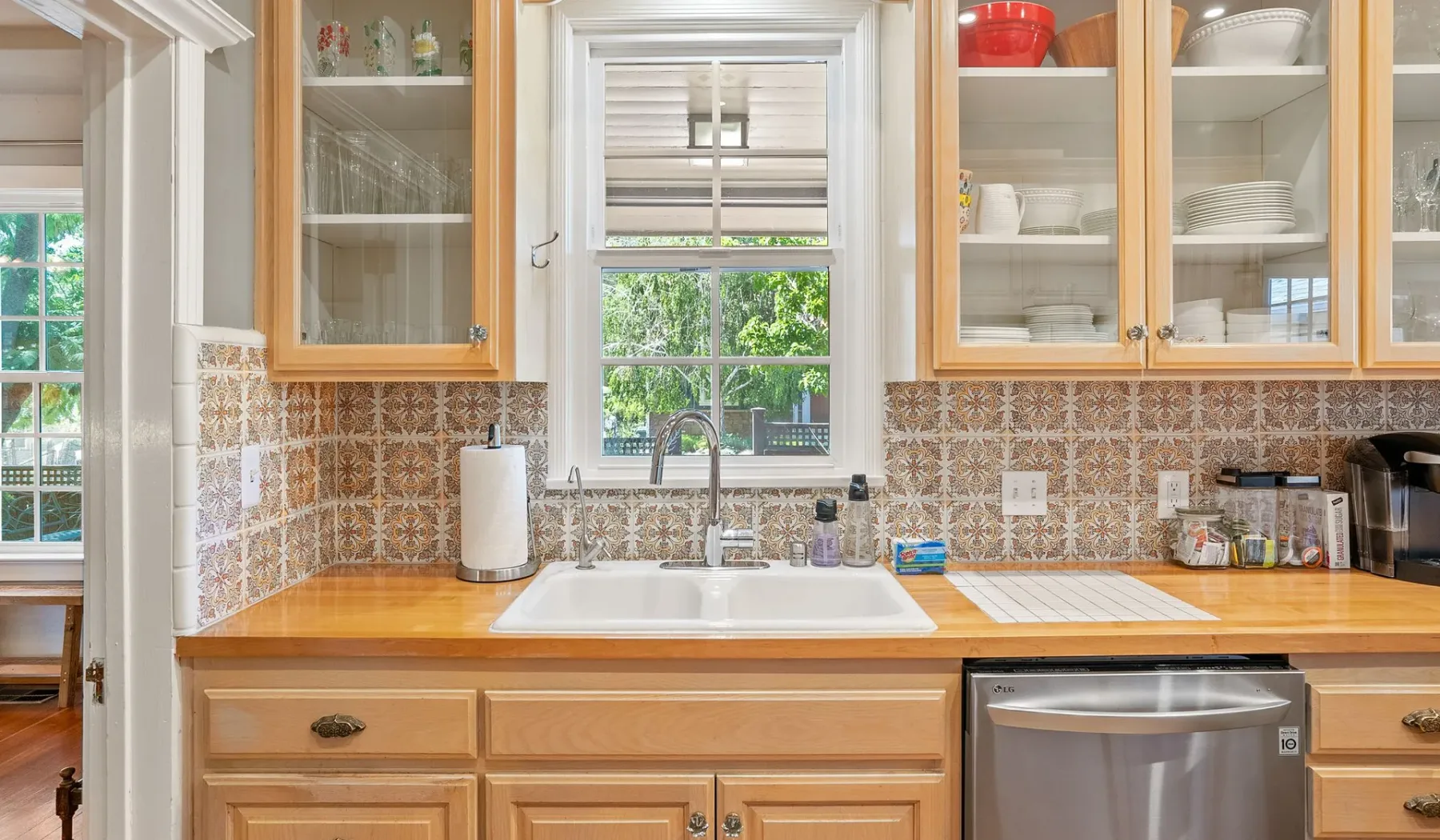 Una cocina luminosa con gabinetes de madera, un fregadero y una ventana sobre la encimera.