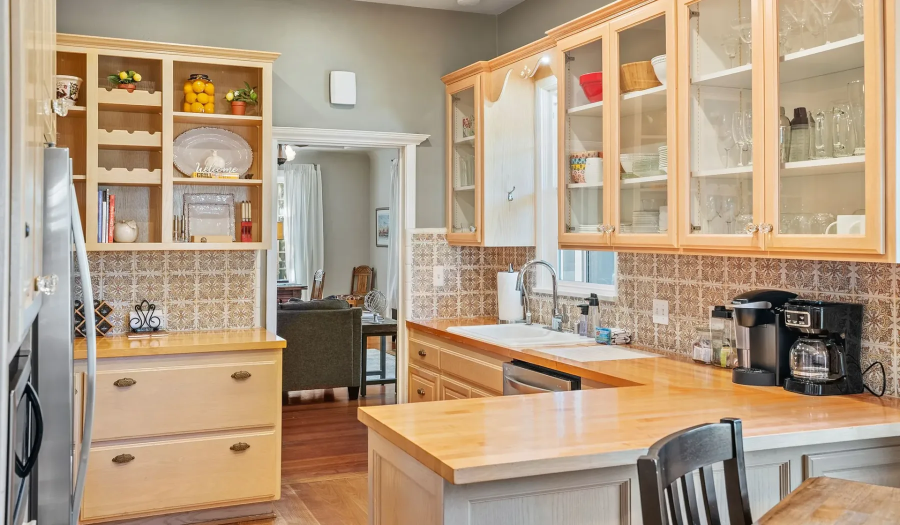 Una cocina con gabinetes de madera clara, salpicadero de azulejos e isla central.