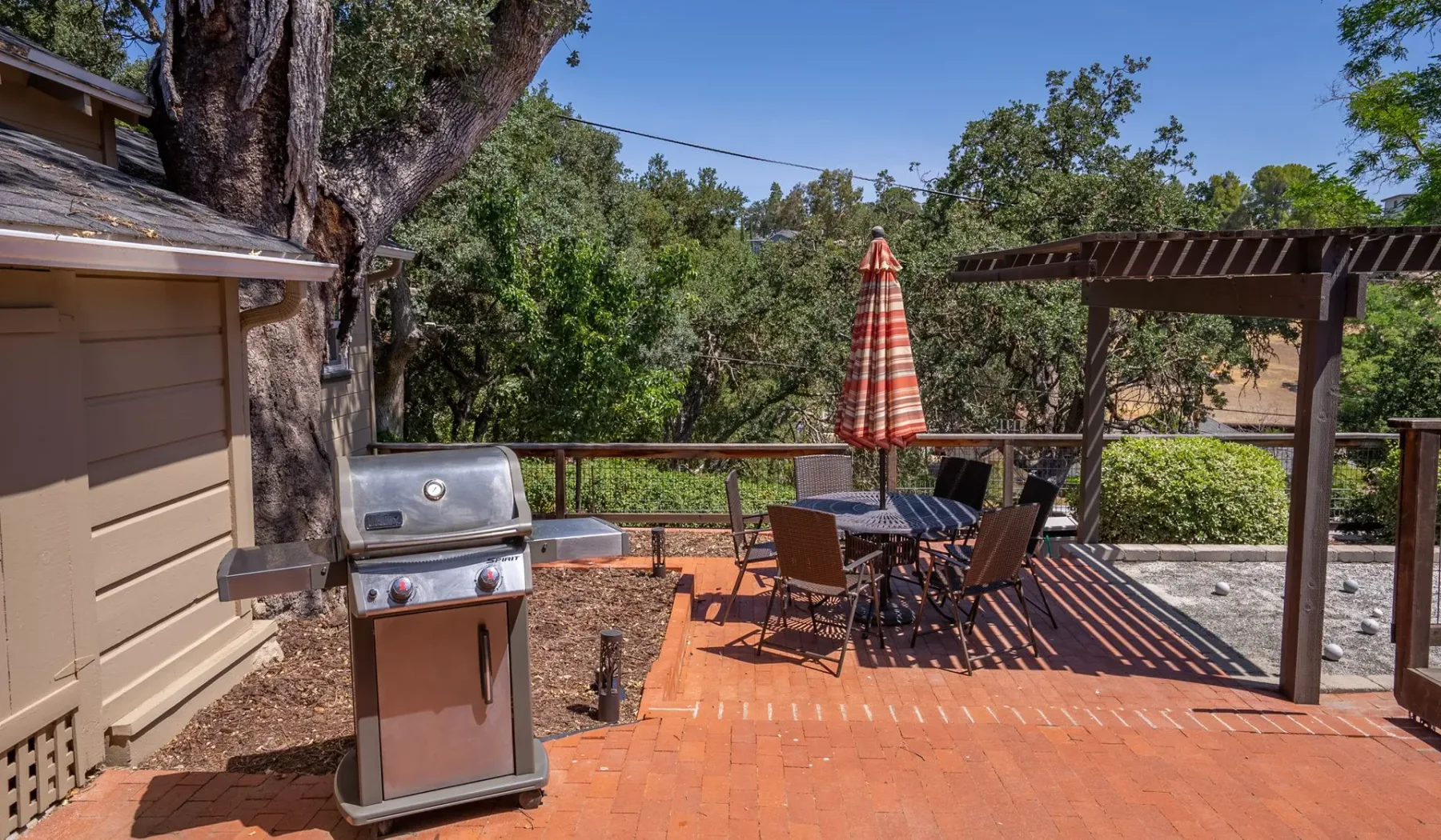 Un patio al aire libre con una parrilla, una mesa de comedor y una zona cubierta para sentarse.
