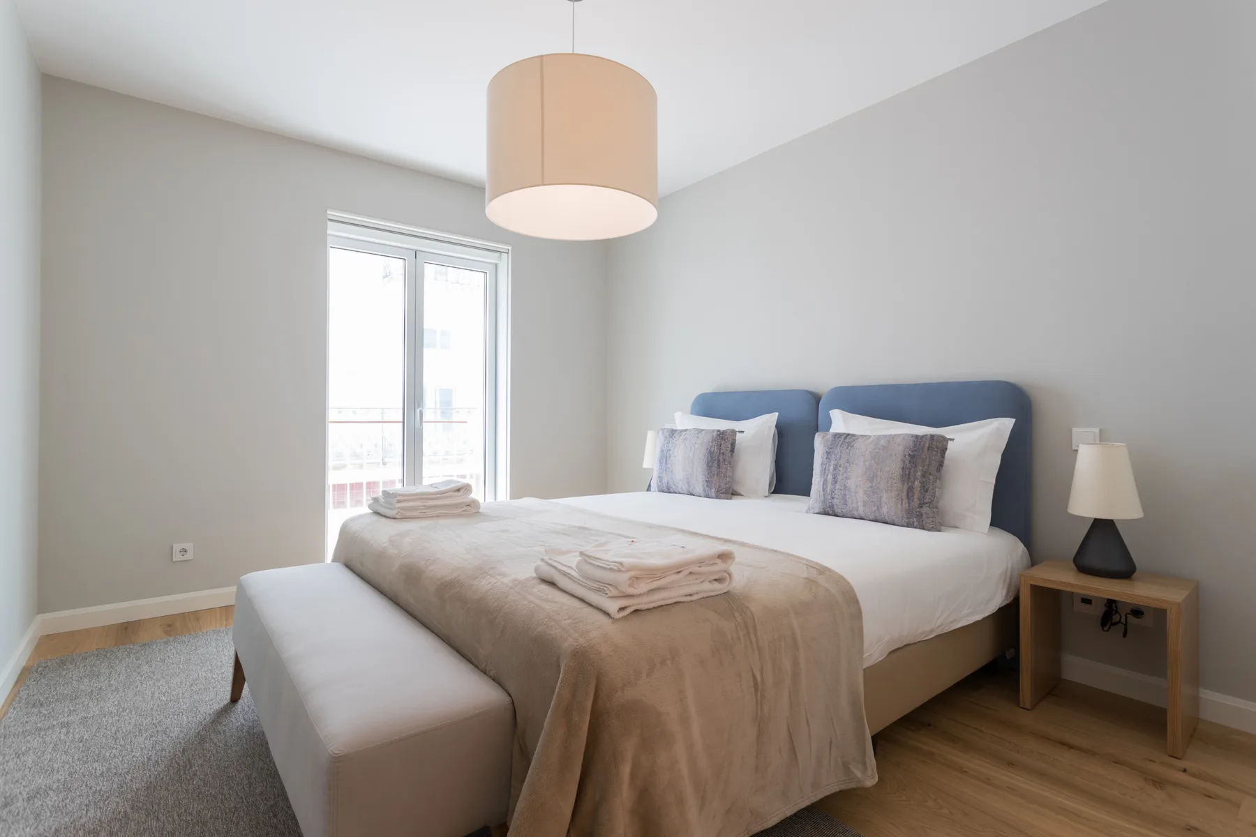 A bright bedroom with a neatly made bed and a window.