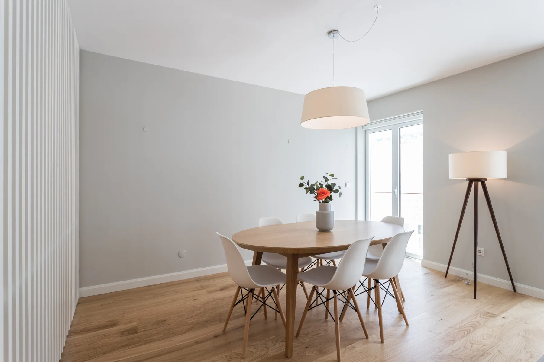 A bright dining area with a wooden table, seating, and a large window.
