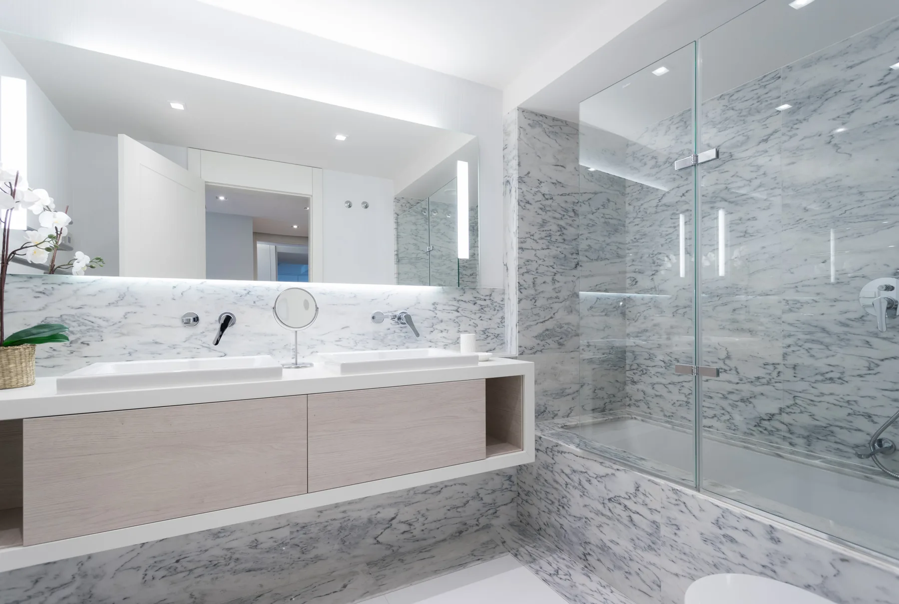 A bright bathroom with a wide vanity and glass shower.