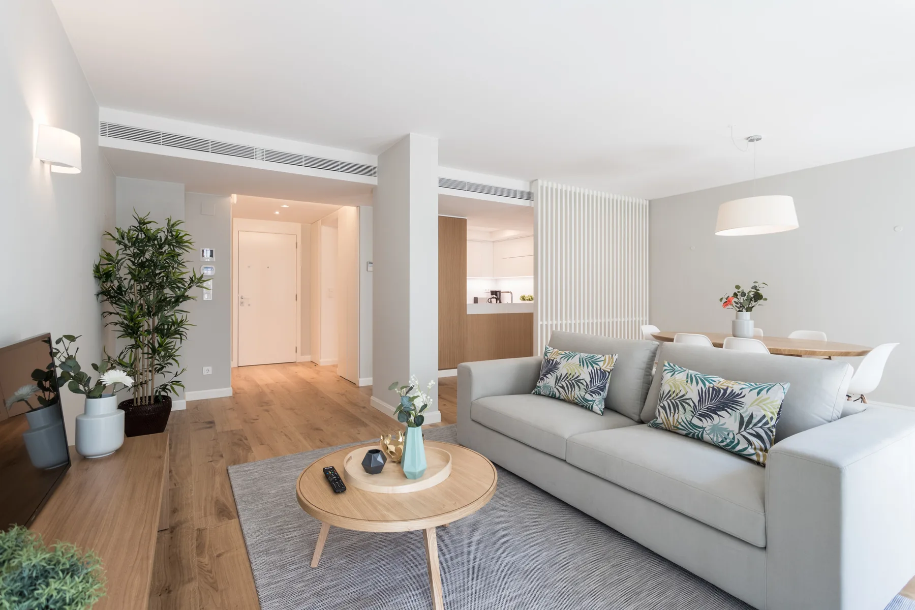 A bright living room with a gray seating area and a round coffee table.