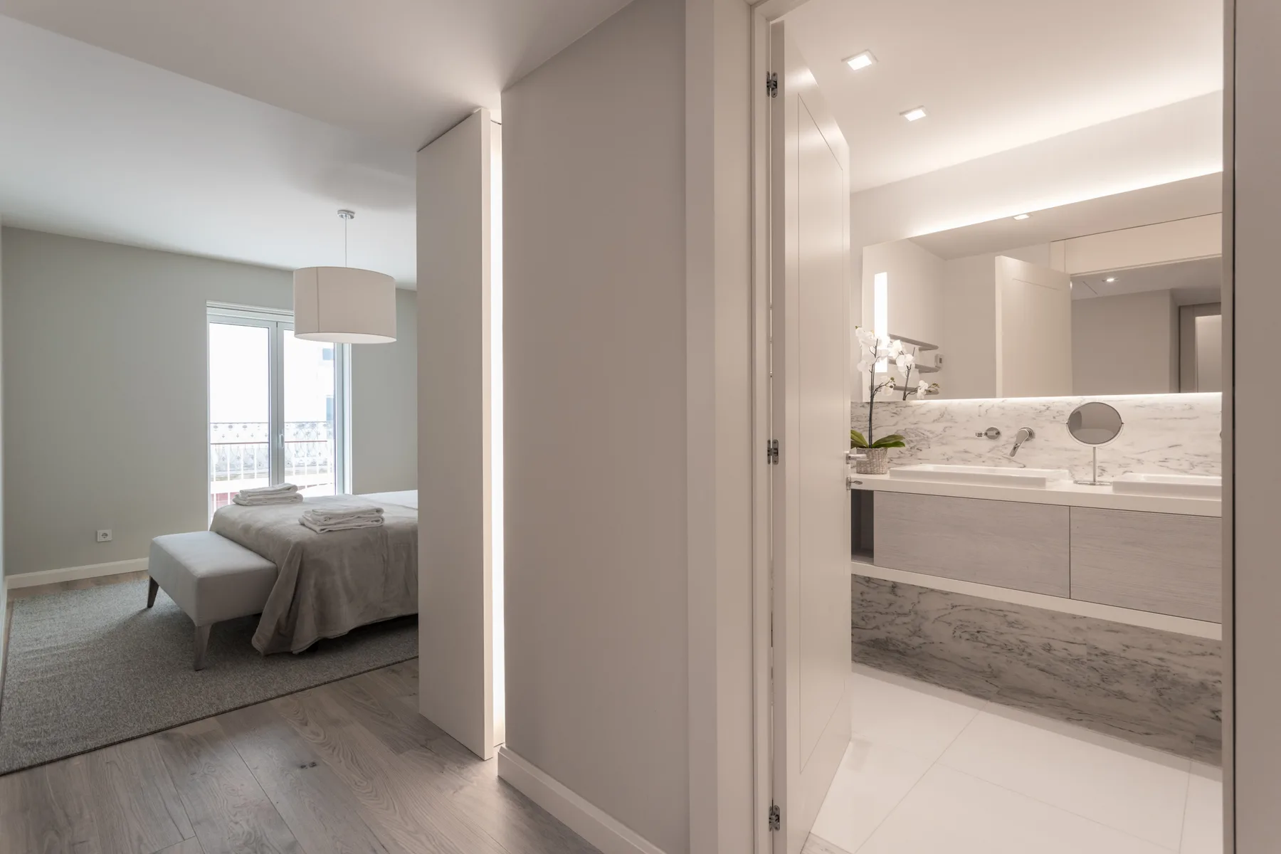 A bedroom opens onto a bathroom with a long vanity and mirror.