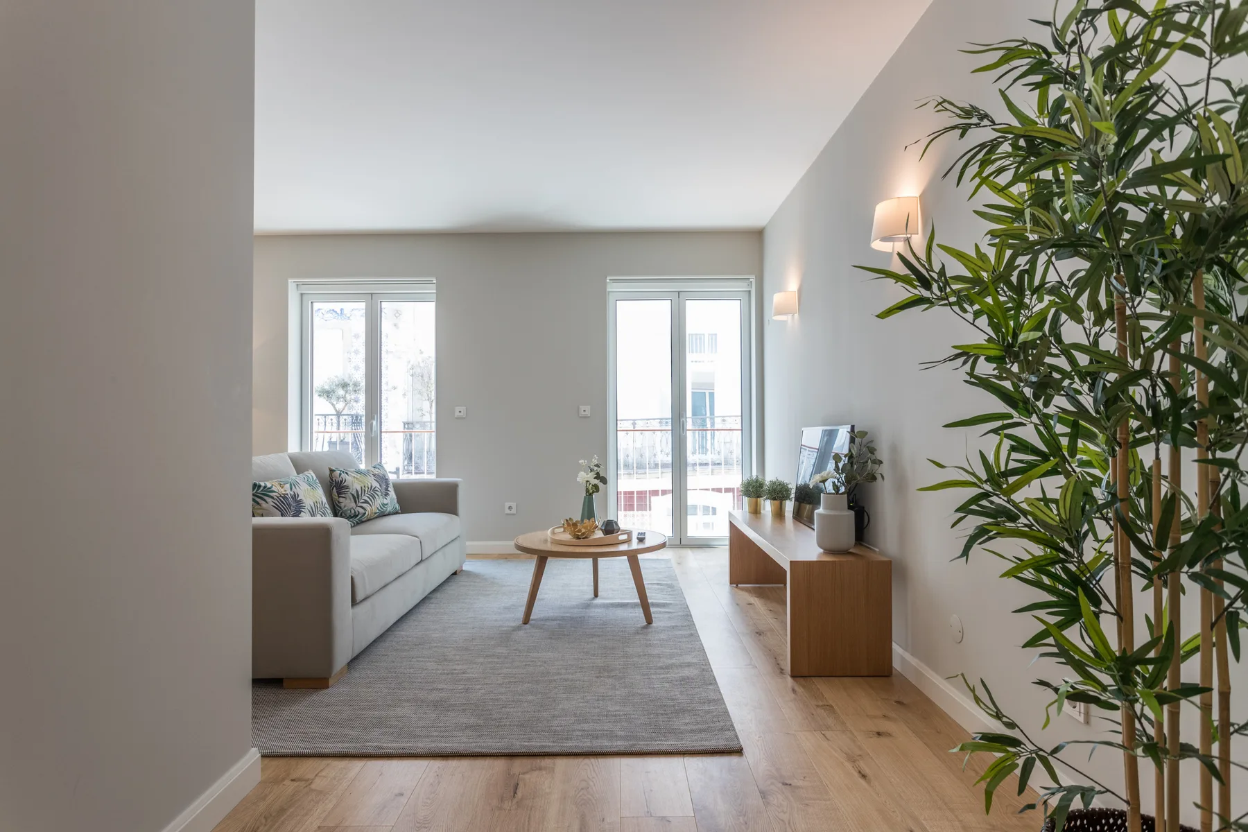 A bright living room with seating, a coffee table, and tall windows.