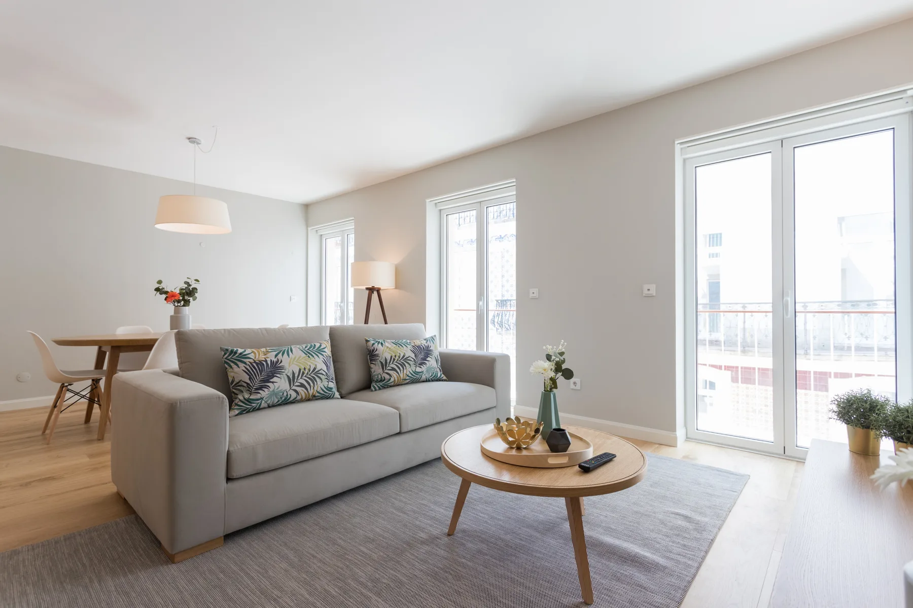 A bright living room with seating and a dining area beside the windows.