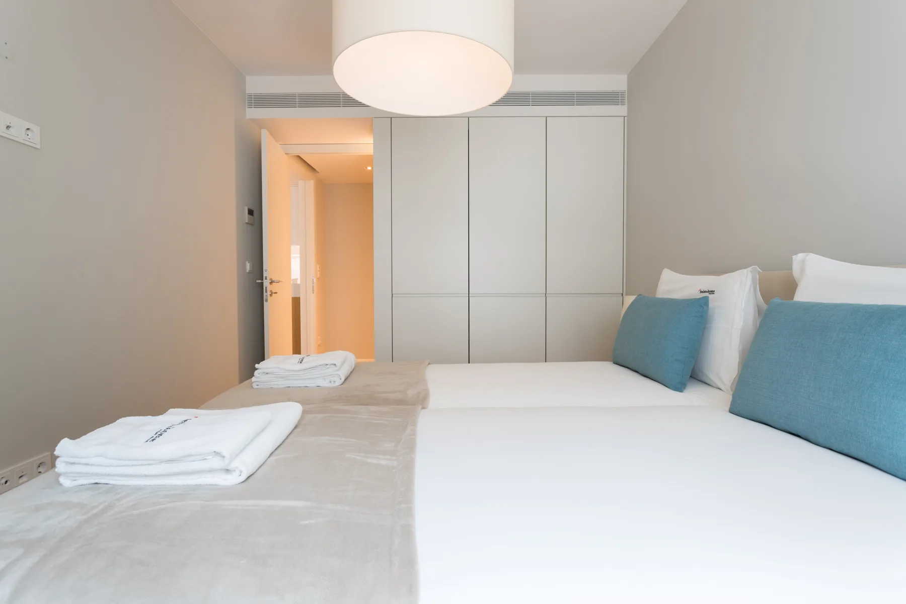 A bright bedroom with a neatly made bed and folded towels.