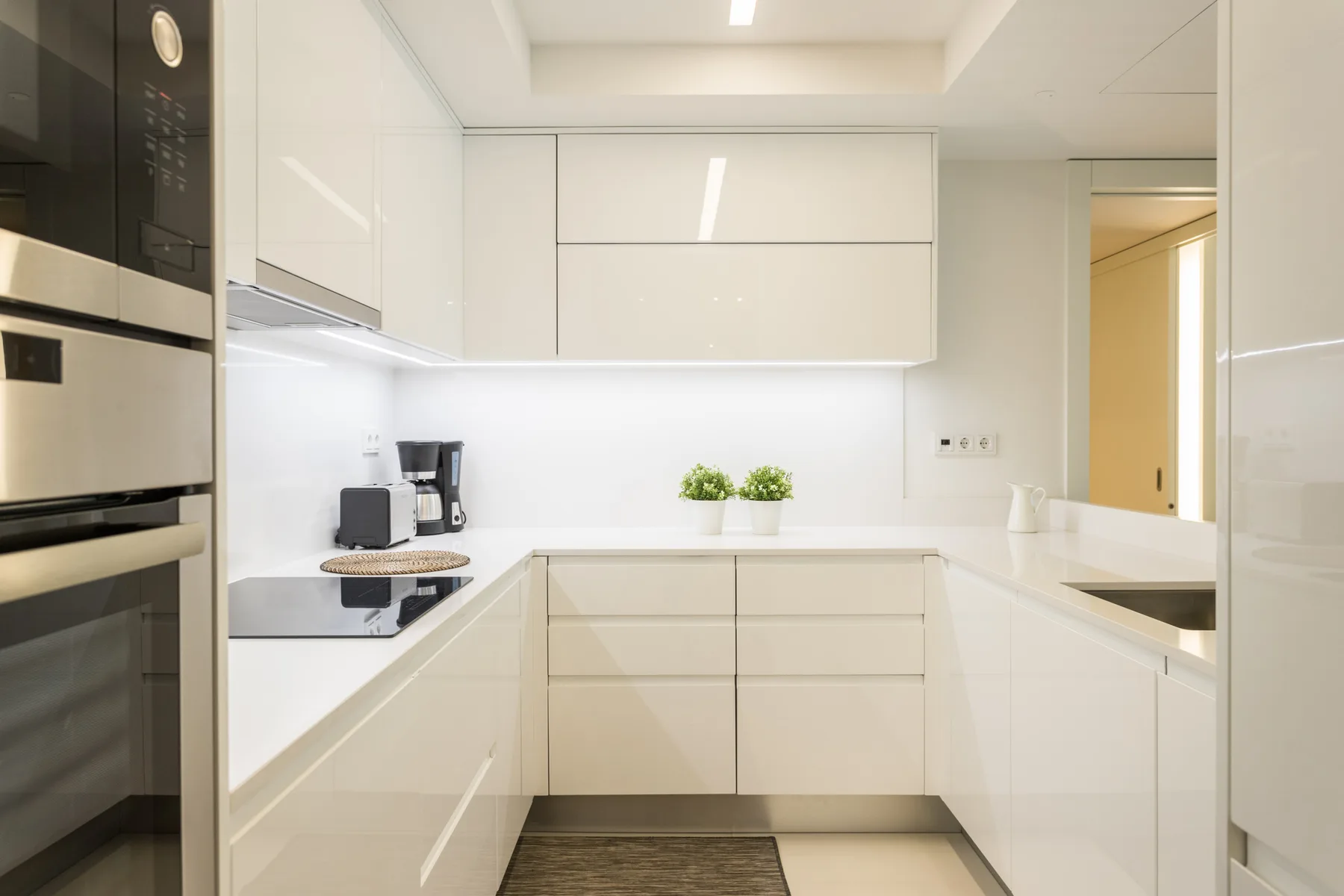A bright modern kitchen with white cabinets and a countertop.