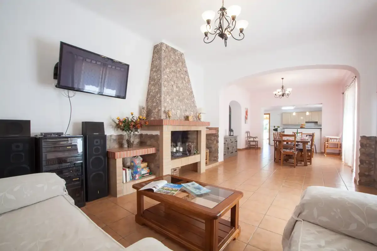 Una sala de estar con chimenea, asientos y un comedor al fondo.