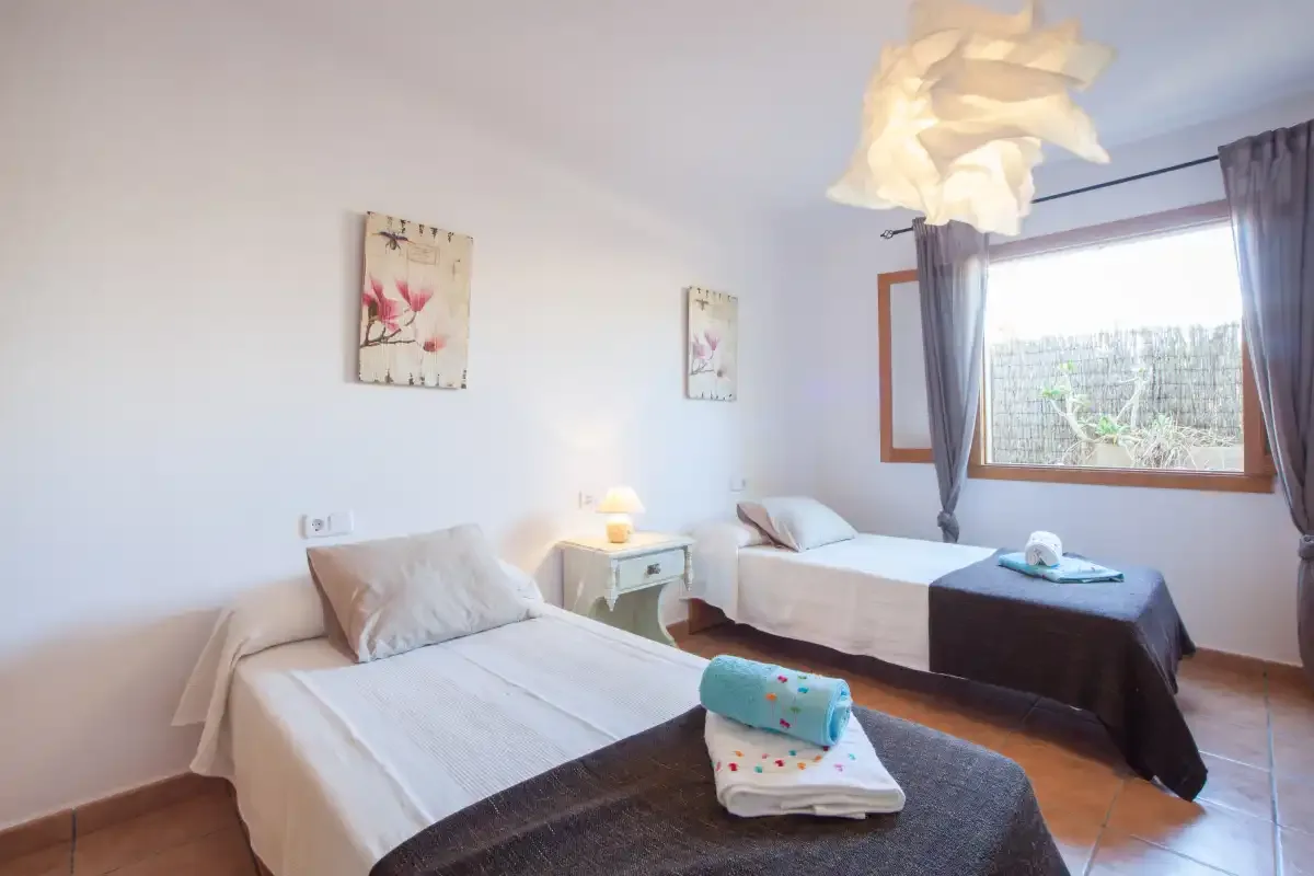 Un dormitorio con dos camas, mesitas de noche y una ventana grande.