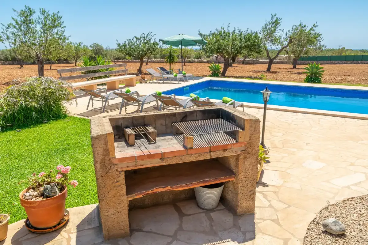 Una zona de piscina al aire libre con una parrilla fija y una terraza alrededor.