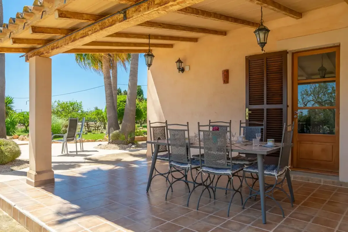 Un patio sombreado con una mesa de comedor y sillas junto al jardín.