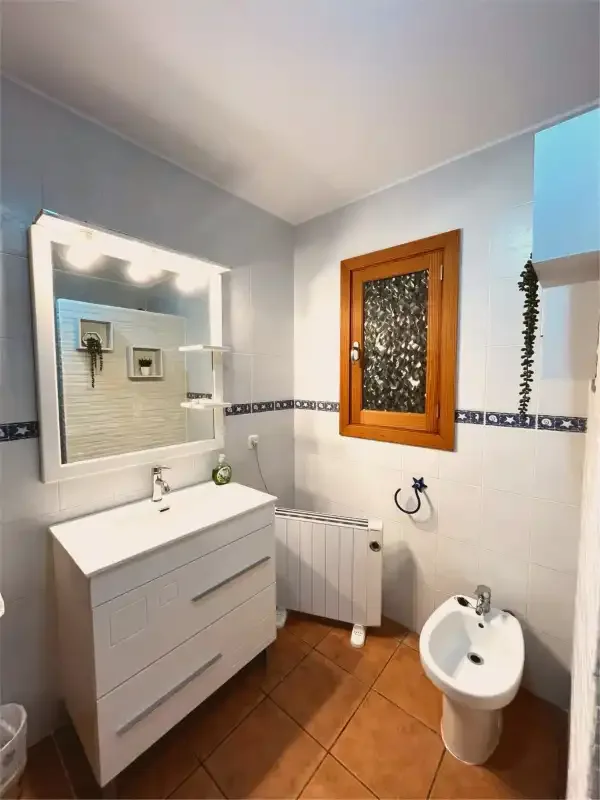 Un baño con lavabo, espejo, ventana y bidé.