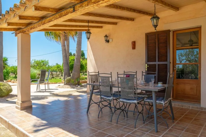 Un patio cubierto con una mesa de comedor y asientos junto a un jardín.