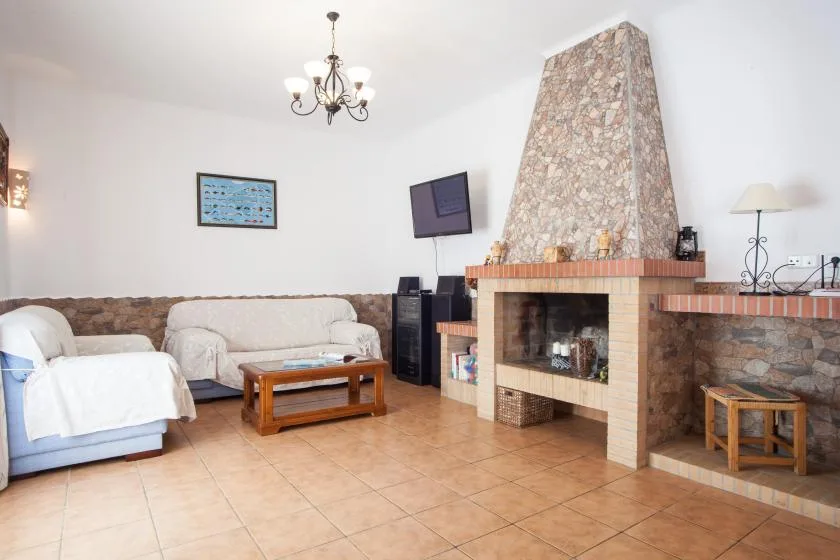 Una sala de estar con asientos claros, una mesa de centro y una gran chimenea.
