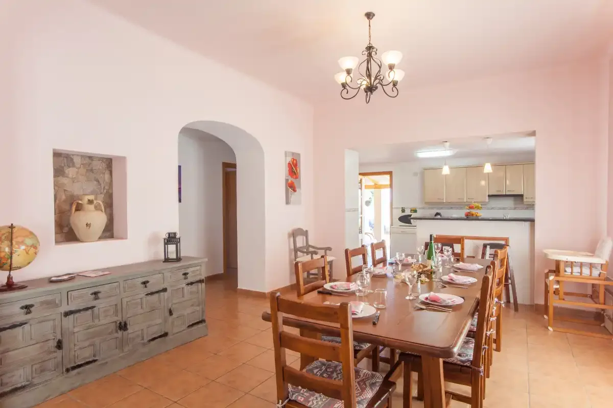 Un comedor con una larga mesa de madera junto a una cocina abierta.