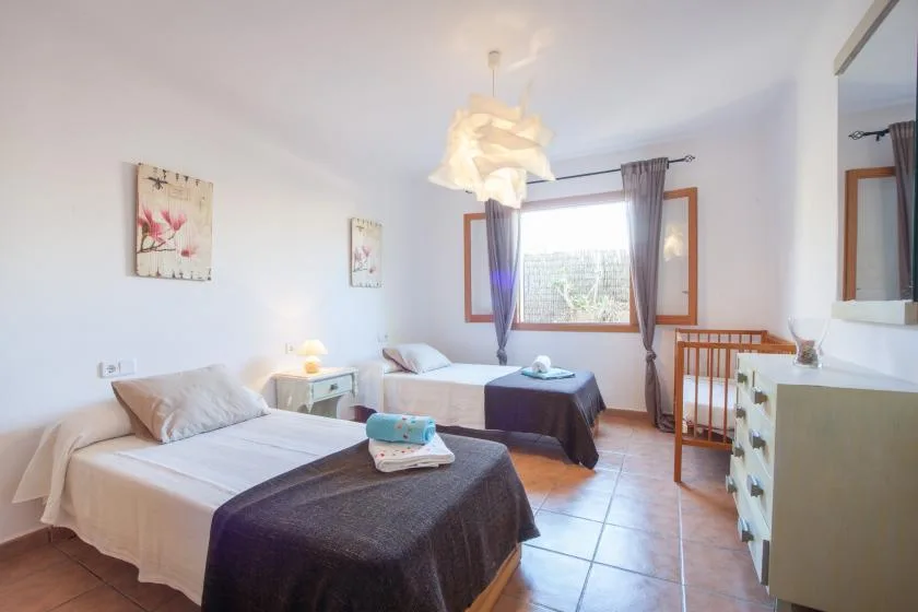 Un dormitorio luminoso con dos camas y una ventana con vistas a la vegetación.
