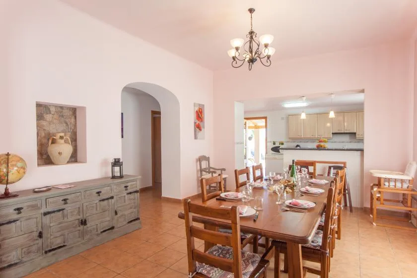 Un comedor con una mesa larga de madera junto a una cocina abierta.