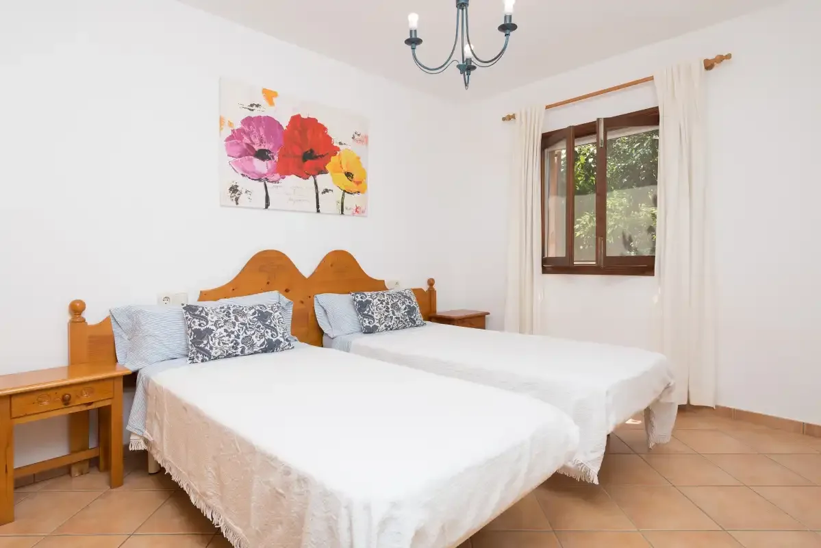A bedroom with two beds, wooden headboards, and a window.