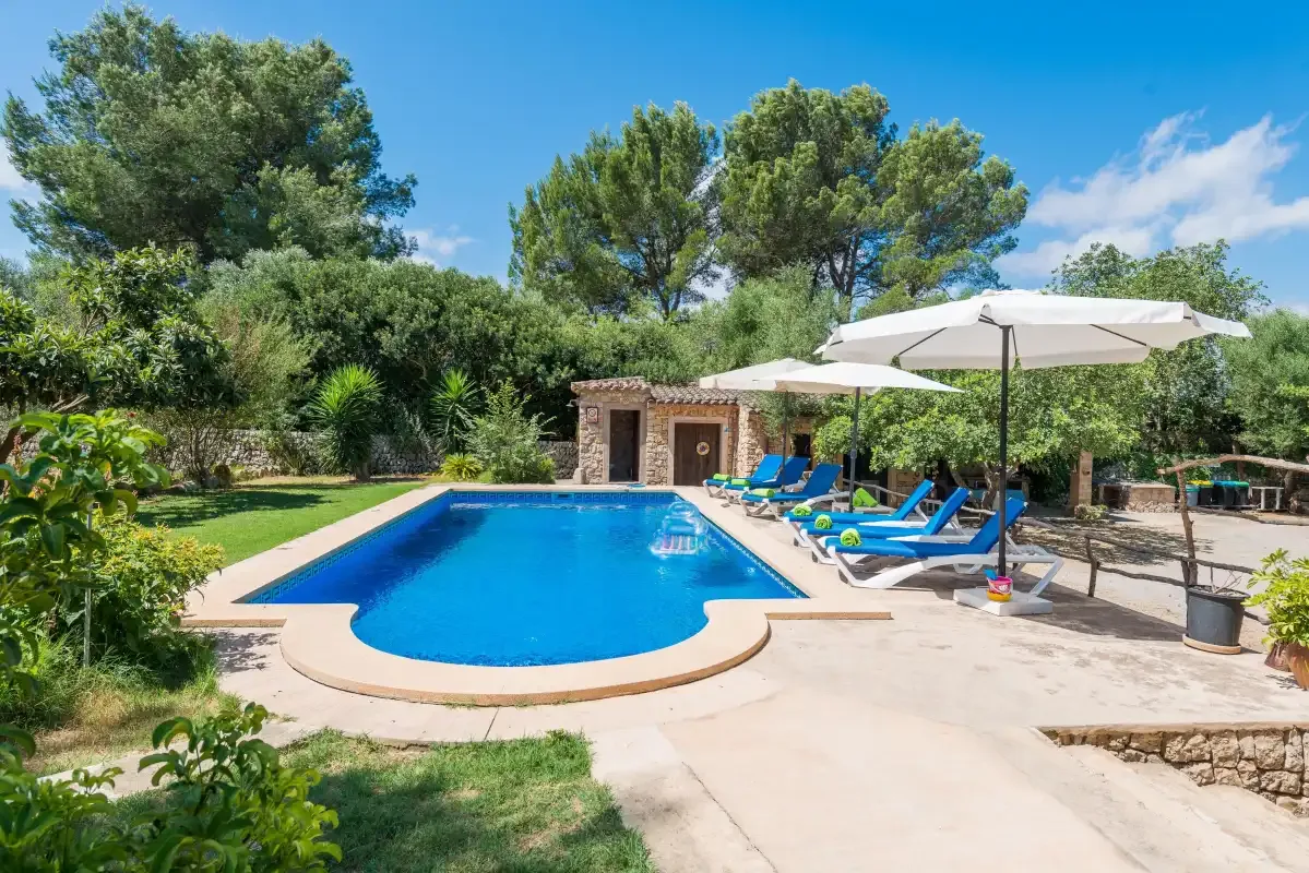 An outdoor swimming pool is surrounded by greenery and lounge seating.
