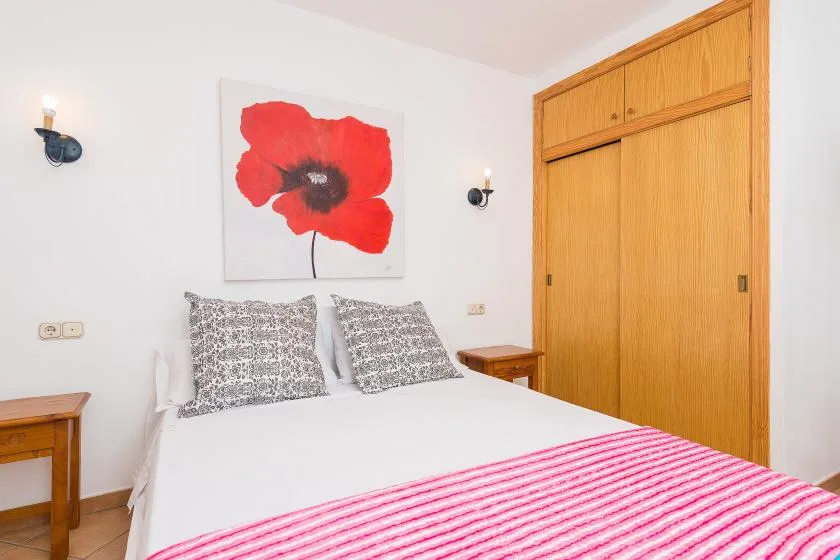 A bedroom with a bed dressed in white and pink-striped bedding.
