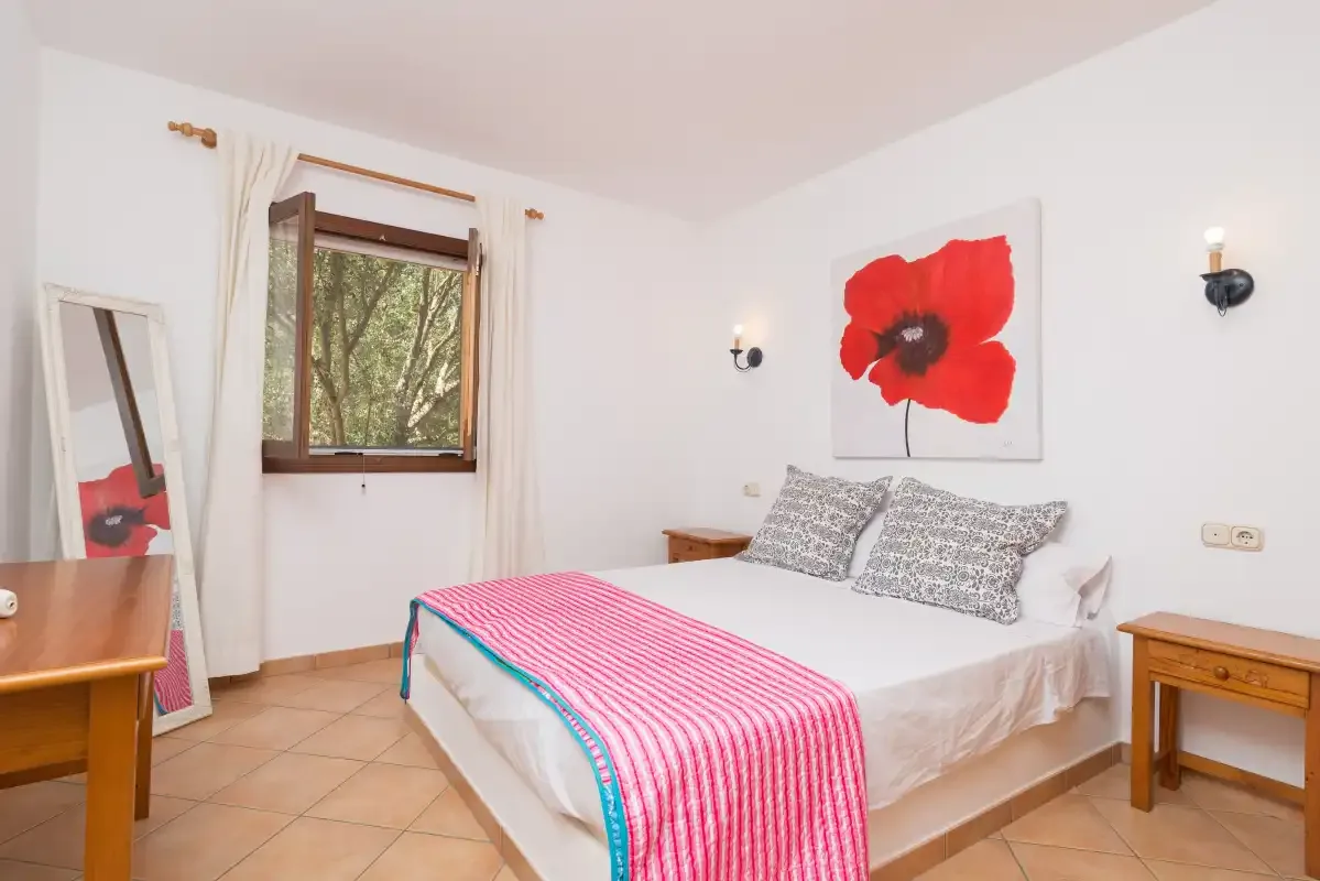 A bedroom with a double bed and a large red flower painting above it.