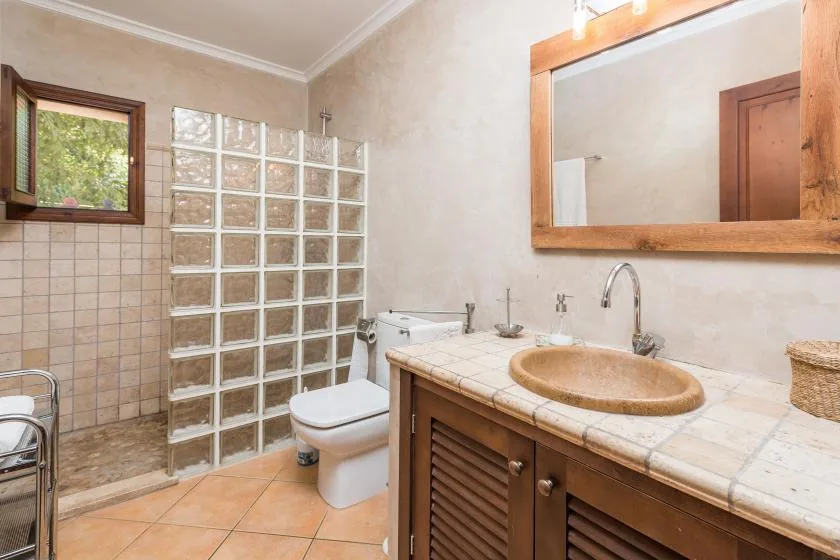 A tiled bathroom with a vanity, sink, and glass-block shower partition.
