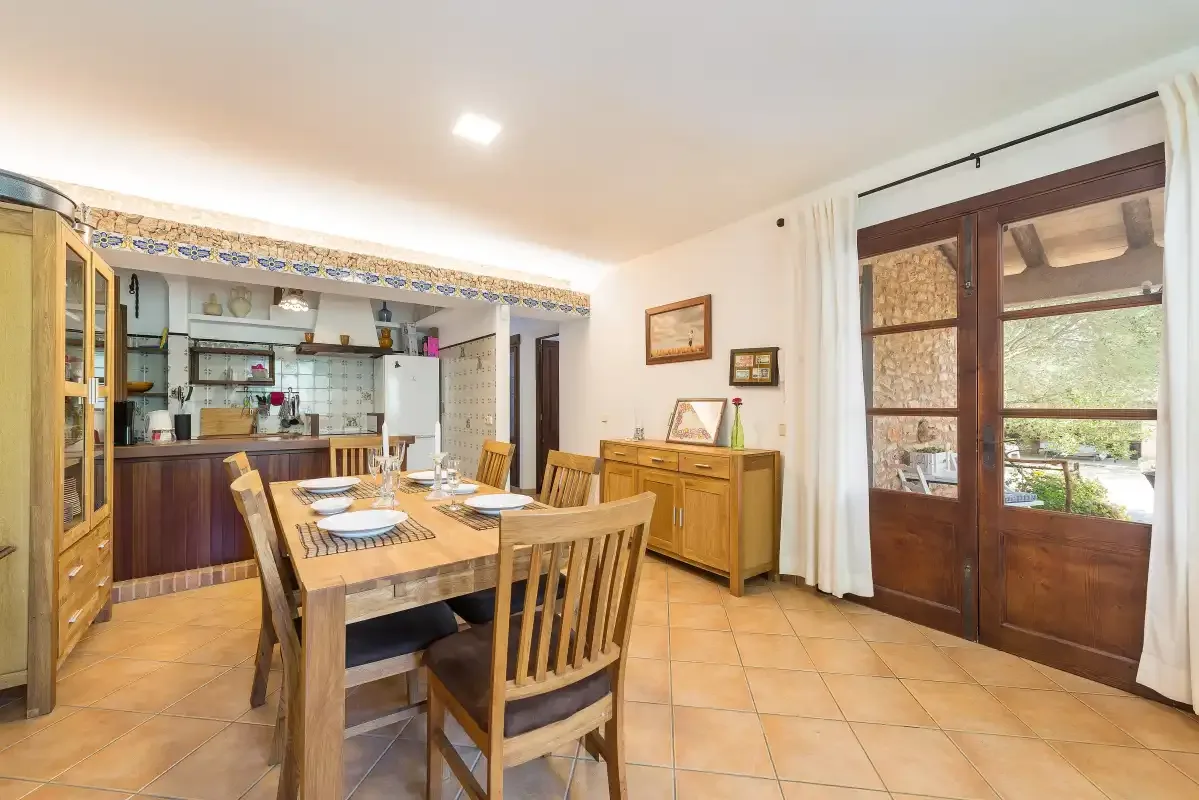 A dining area with a wooden table beside an open kitchen.