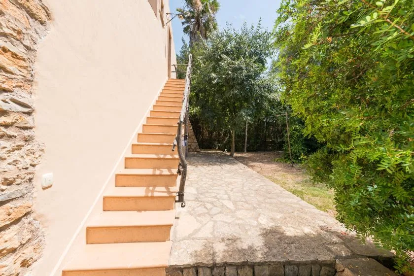 An outdoor staircase leads up beside a paved courtyard surrounded by trees.