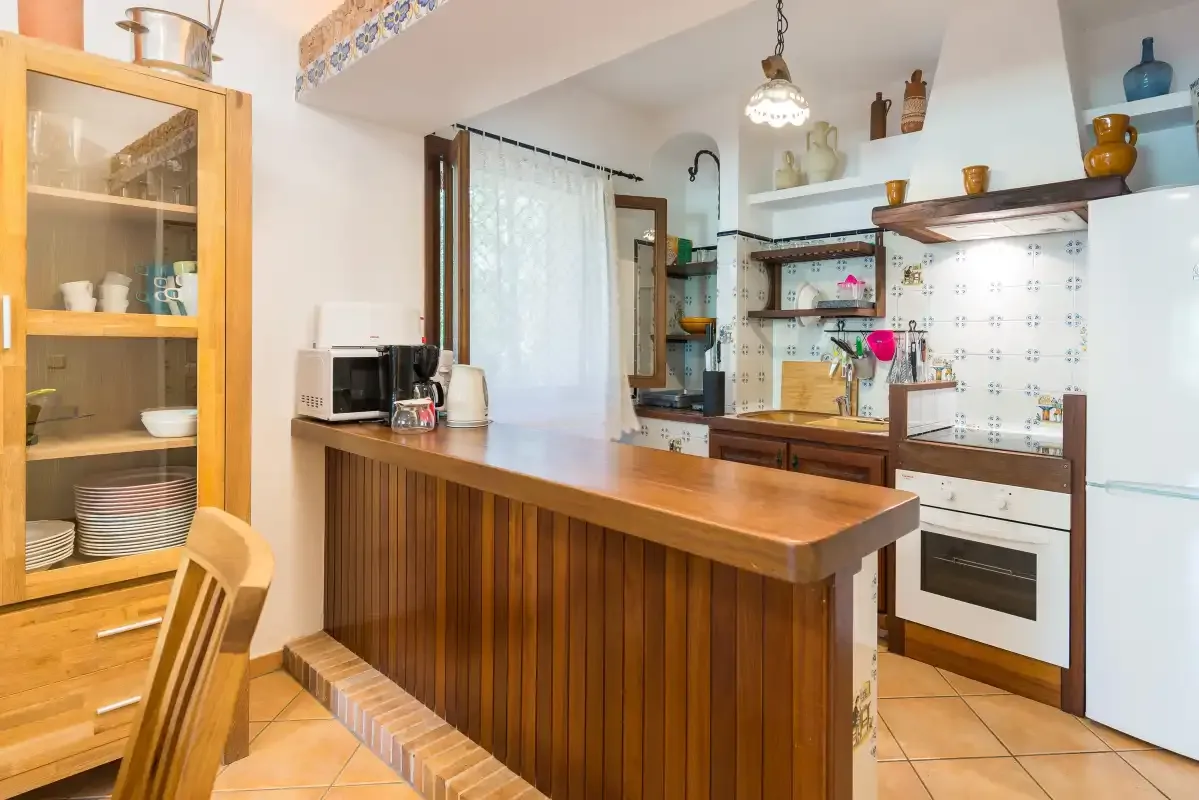 A kitchen with a wooden island, built-in oven, and open shelving.