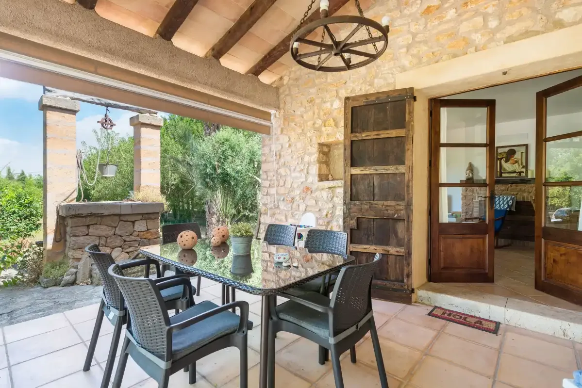 A covered patio dining area opens onto a garden, with a table and chairs.