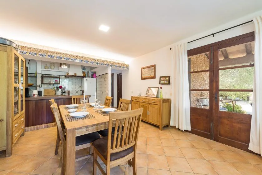 A dining area with a wooden table and chairs beside the kitchen.