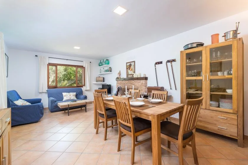 A dining and living room with a wooden table and seating by a window.