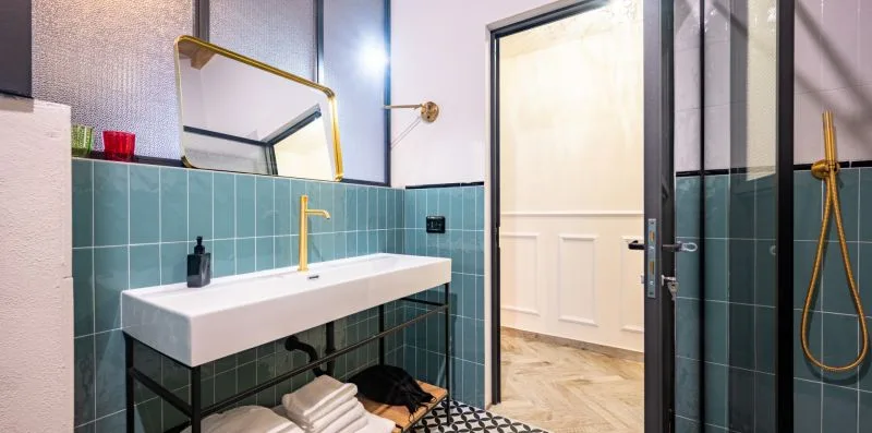 Un baño con azulejos, lavabo suspendido y ducha de vidrio.