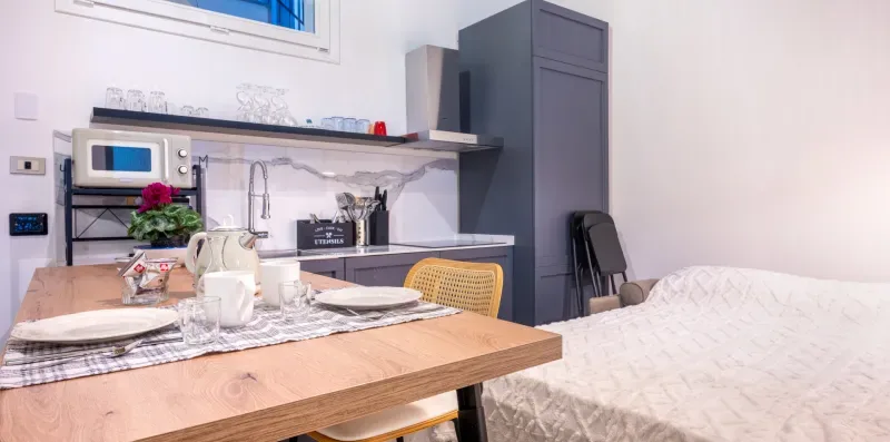 Una pequeña zona de comedor y cocina con una mesa de madera y electrodomésticos sobre la encimera.
