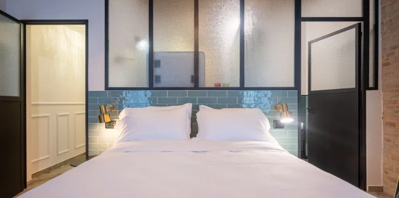 Un dormitorio con una cama bien tendida y una pared de azulejos detrás.