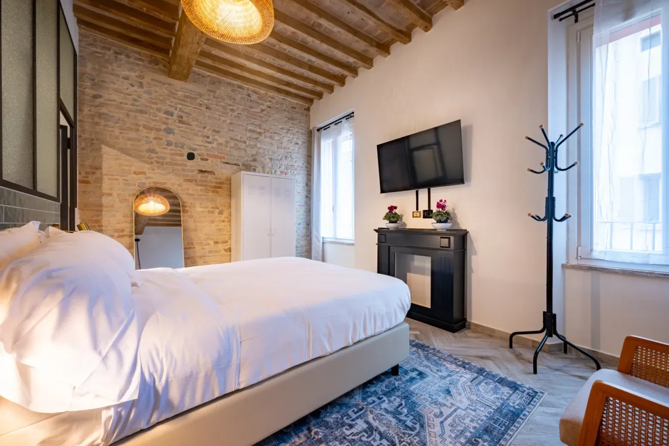 Un dormitorio con una cama grande, vigas a la vista y un televisor en la pared.