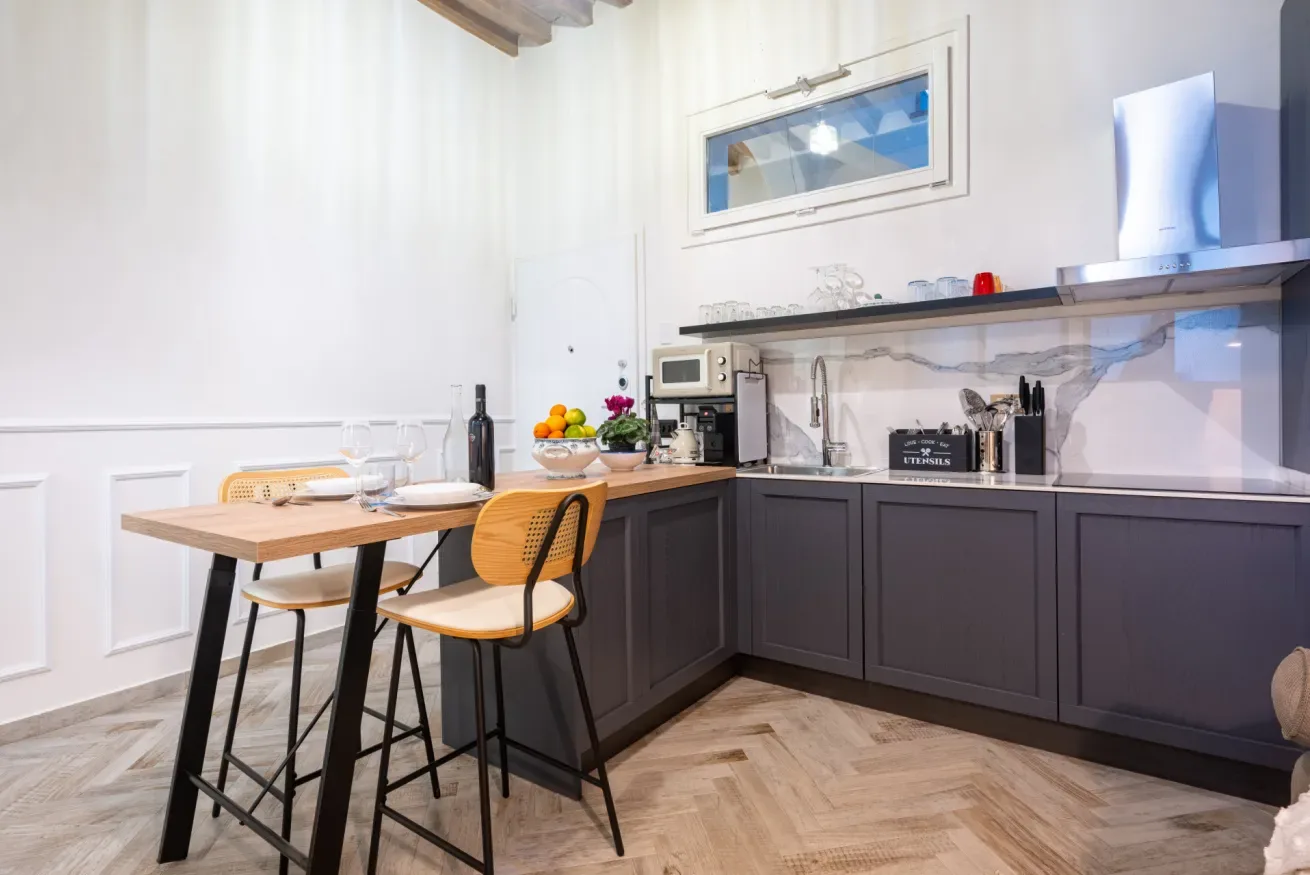Una cocina con gabinetes oscuros y una mesa junto a la encimera.
