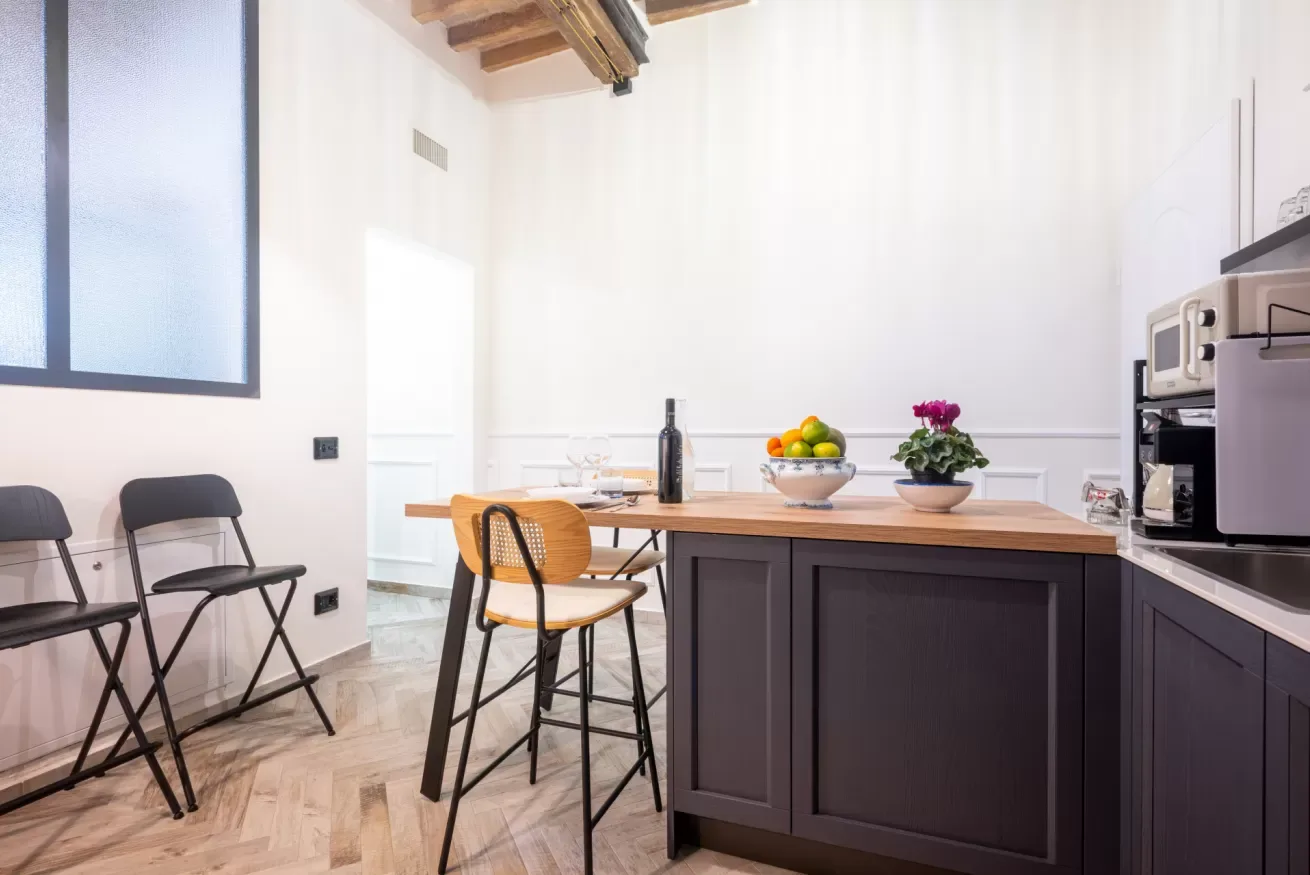 Una cocina y comedor con una isla oscura, una mesa y sillas.