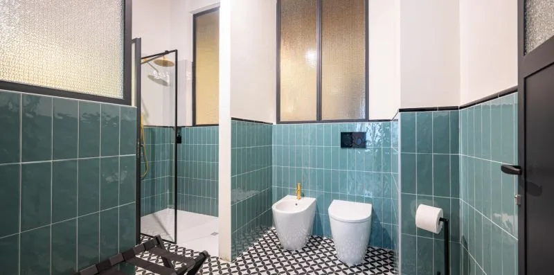 Un baño alicatado con inodoro, bidé y zona de ducha.