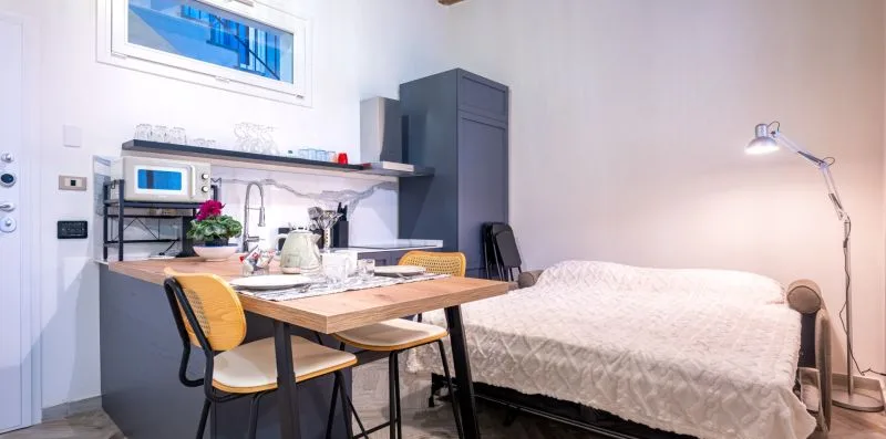 Un dormitorio compacto con una mesa junto a la cama y una lámpara de pared.