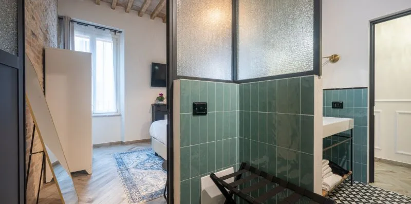 Un baño con paredes de azulejos verdes, un lavabo y una mampara de vidrio.