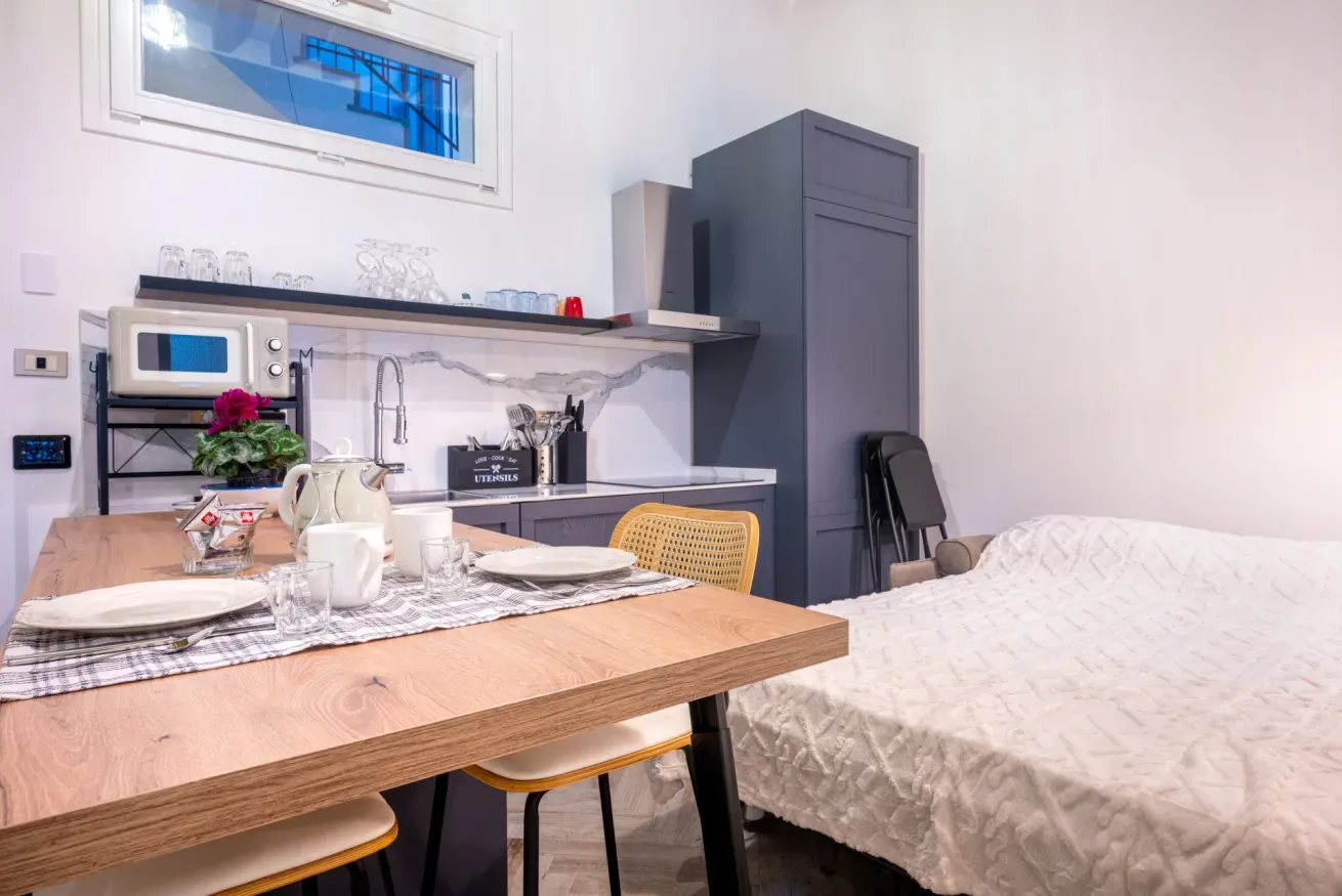 Una mesa de comedor y una cama comparten una habitación compacta con una pequeña cocina.