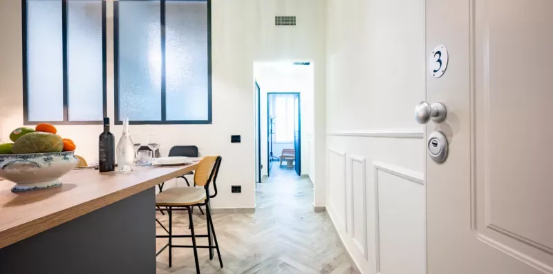 Un comedor luminoso con una mesa de madera, sillas y una puerta hacia otra habitación.