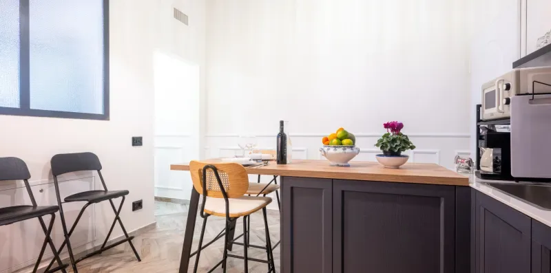 Una cocina y comedor luminosos con una barra, una mesa y asientos.